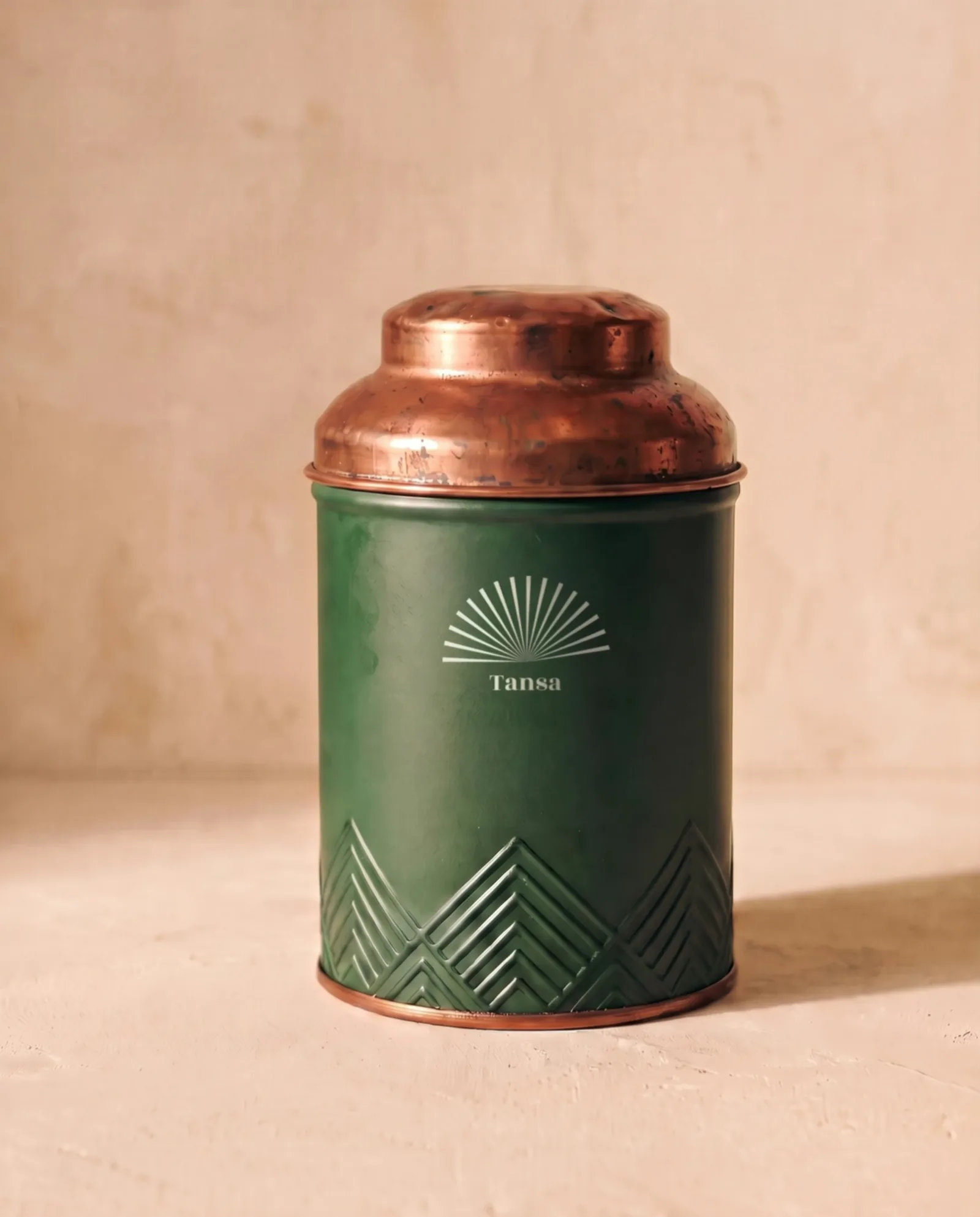 The house tin: bottle green with a copper lid and a cream sunburst.