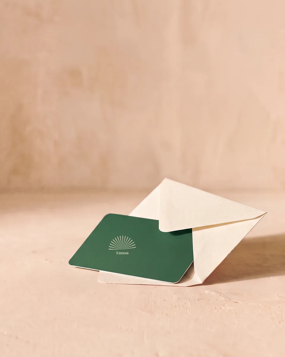 A green gift card half tucked into a cream envelope.