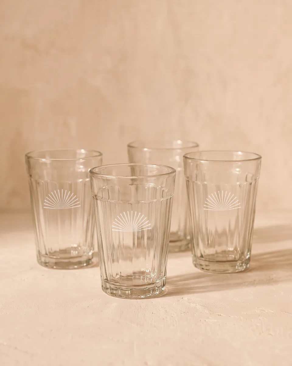 Four ribbed chai glasses, each etched with a small sunburst.