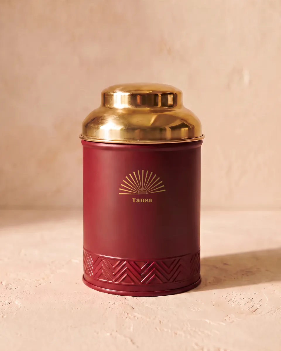 The garden edition tin: oxblood red with a brass lid and a brass sunburst.
